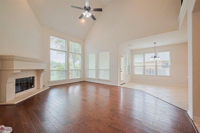 19339 Oxford Haven Dr, Cypress, TX 77433 - unfurnished living room with high vaulted ceiling, a chandelier, wood-type flooring, a glass covered fireplace, and ceiling fan