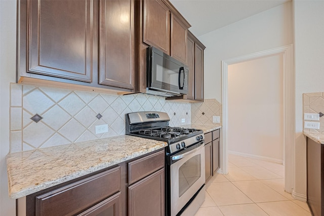 19339 Oxford Haven Dr, Cypress, TX 77433 - kitchen featuring stainless steel gas range oven, black microwave, light stone countertops, dark brown cabinets, and backsplash