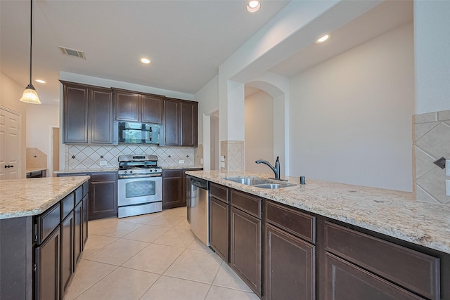 19339 Oxford Haven Dr, Cypress, TX 77433 - kitchen featuring appliances with stainless steel finishes, light tile patterned floors, dark brown cabinets, backsplash, and light stone counters