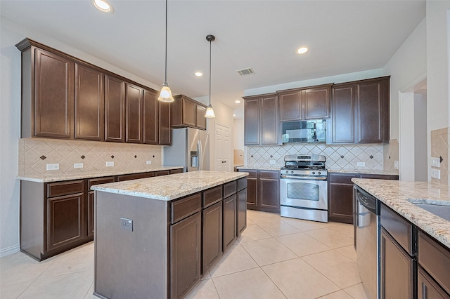 19339 Oxford Haven Dr, Cypress, TX 77433 - kitchen with stainless steel appliances, dark brown cabinets, decorative backsplash, a kitchen island, and hanging light fixtures
