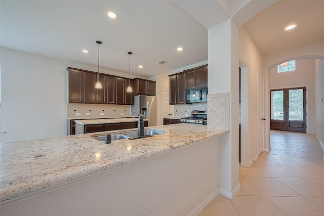 19339 Oxford Haven Dr, Cypress, TX 77433 - kitchen with stainless steel appliances, arched walkways, dark brown cabinetry, tasteful backsplash, and light tile patterned floors
