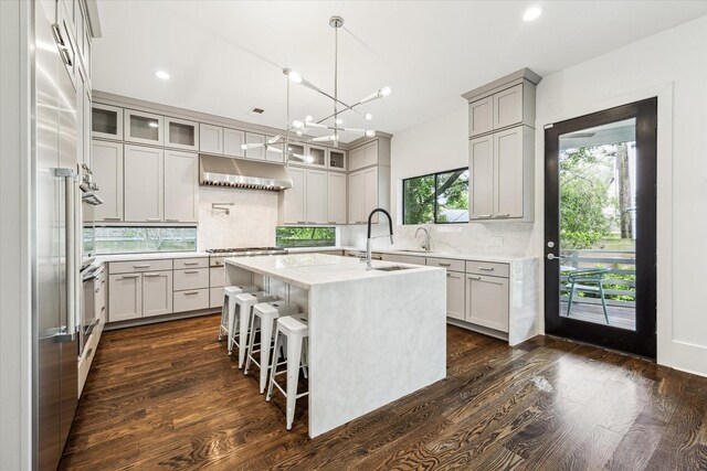 1010 Waltway Dr, Houston, TX 77008 - kitchen with ventilation hood, backsplash, an island with sink, dark wood-type flooring, and recessed lighting