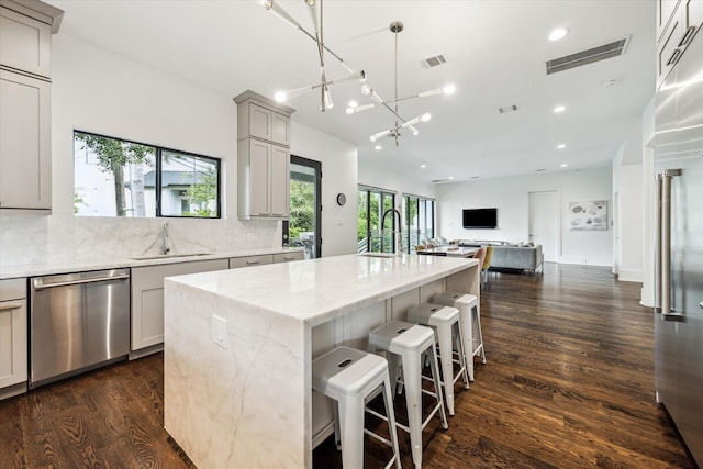 1010 Waltway Dr, Houston, TX 77008 - kitchen featuring appliances with stainless steel finishes, gray cabinetry, dark wood-style floors, decorative backsplash, and open floor plan