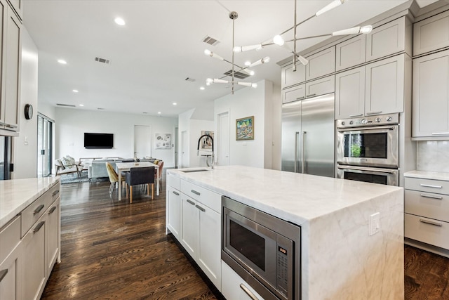 1010 Waltway Dr, Houston, TX 77008 - kitchen featuring built in appliances, recessed lighting, open floor plan, light stone counters, and dark wood-style flooring