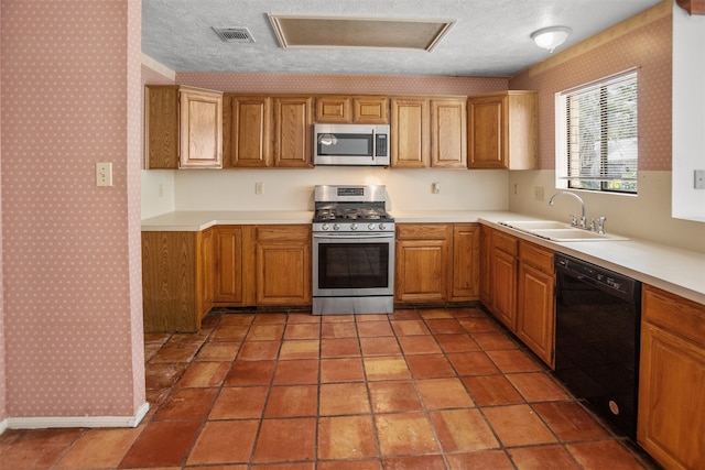14202 Double Pine Dr, Houston, TX 77015 - kitchen featuring appliances with stainless steel finishes, wallpapered walls, light countertops, a textured ceiling, and brown cabinetry