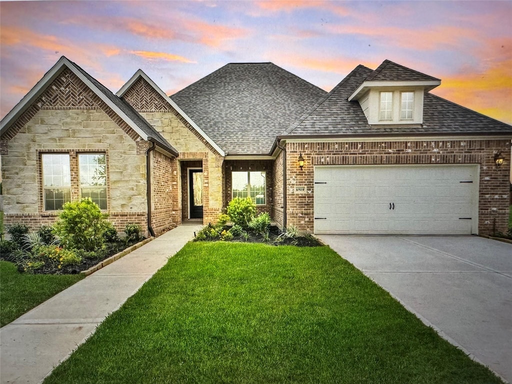 10519 Lantana Pass, Missouri City, TX 77459 - french country inspired facade featuring a front lawn, an attached garage, brick siding, concrete driveway, and roof with shingles