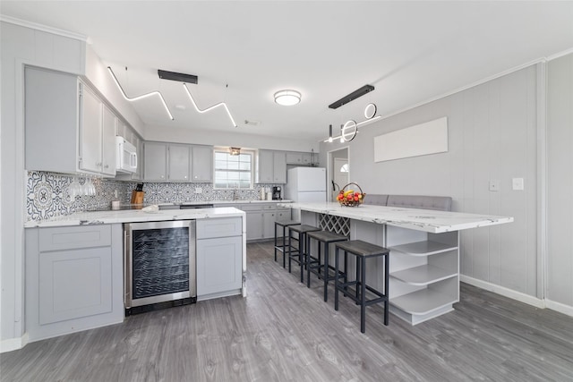 610 Seashell Dr, Freeport, TX 77541 - kitchen featuring wine cooler, white appliances, open shelves, gray cabinets, and light wood finished floors
