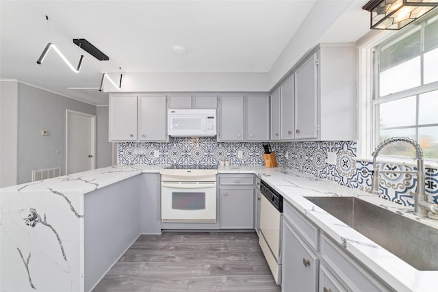 610 Seashell Dr, Freeport, TX 77541 - kitchen with white appliances, a peninsula, wood finished floors, and tasteful backsplash