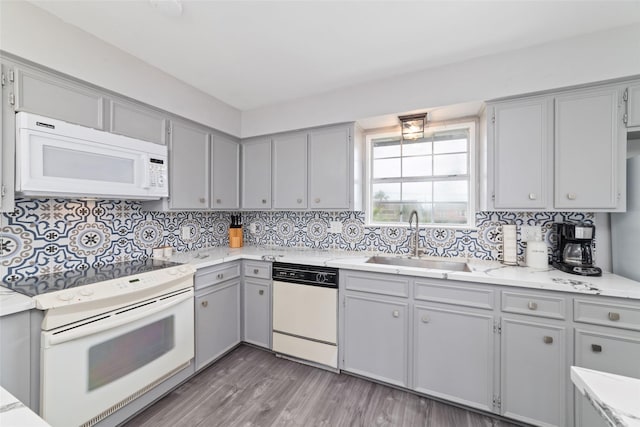 610 Seashell Dr, Freeport, TX 77541 - kitchen with white appliances, gray cabinetry, decorative backsplash, and light wood finished floors