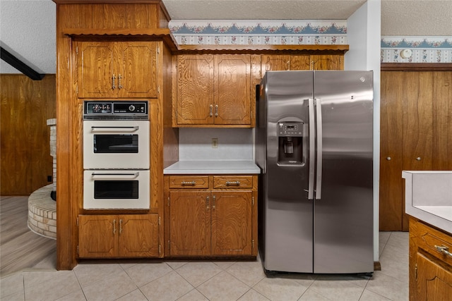 14115 Lantern Ln, Houston, TX 77015 - kitchen with stainless steel fridge with ice dispenser, white double oven, brown cabinets, light countertops, and light tile patterned floors