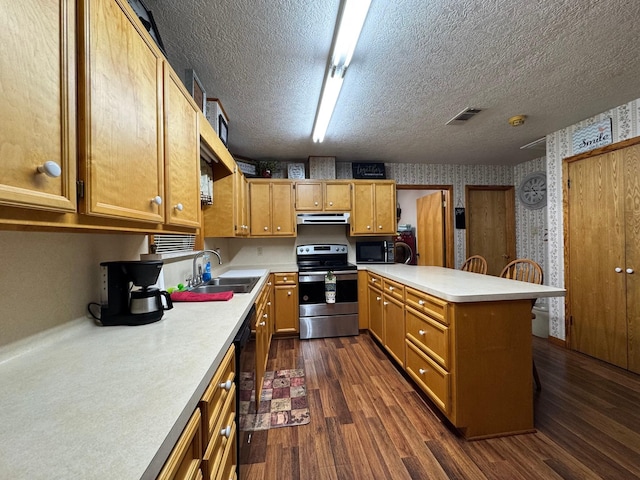 147 County Road 4772, Warren, TX 77664 - kitchen with black appliances, a peninsula, under cabinet range hood, light countertops, and wallpapered walls