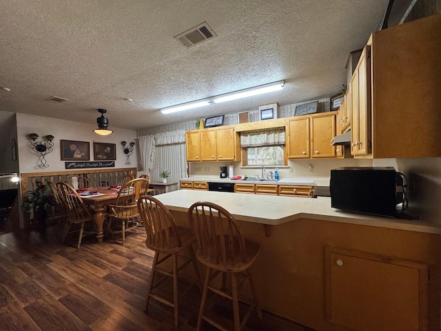 147 County Road 4772, Warren, TX 77664 - kitchen featuring under cabinet range hood, dark wood-type flooring, light countertops, a peninsula, and a textured ceiling