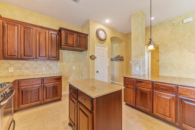 18419 W Willow Oak Bend Dr, Cypress, TX 77433 - kitchen with stainless steel gas stove, arched walkways, light tile patterned floors, light stone countertops, and hanging light fixtures