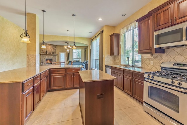 18419 W Willow Oak Bend Dr, Cypress, TX 77433 - kitchen featuring stainless steel appliances, a brick fireplace, tasteful backsplash, light stone counters, and recessed lighting