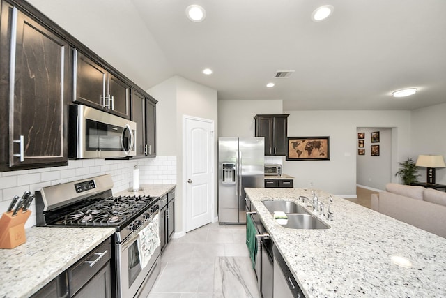 29530 Patricias Way, Katy, TX 77494 - kitchen featuring stainless steel appliances, tasteful backsplash, dark brown cabinets, open floor plan, and light stone countertops