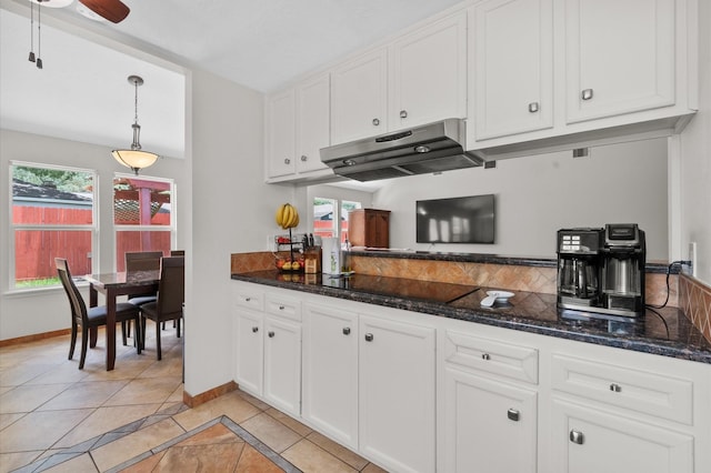 706 Geronimo Ct, Katy, TX 77450 - kitchen with under cabinet range hood, black electric stovetop, white cabinets, and dark stone countertops