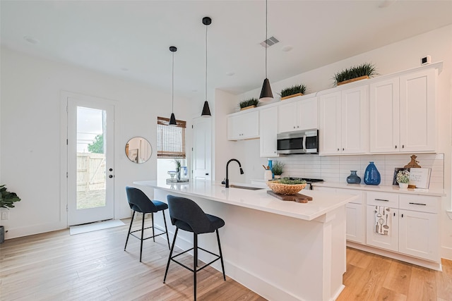 2710 Bostic St, Houston, TX 77093 - kitchen with stainless steel microwave, tasteful backsplash, light wood-type flooring, and white cabinets