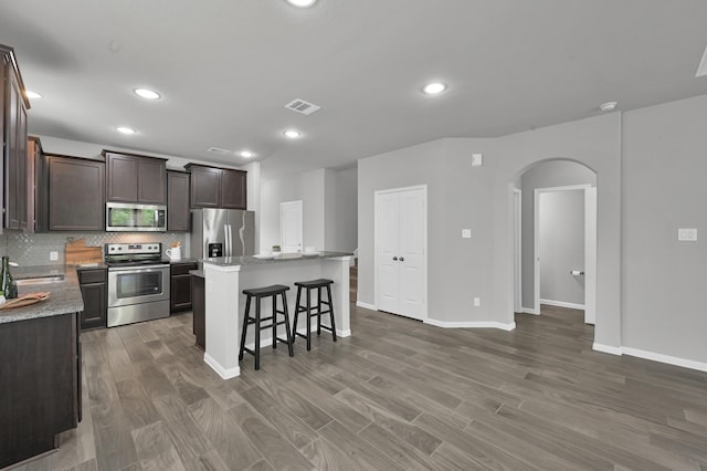 13310 Hidden Valley Dr, Montgomery, TX 77356 - kitchen with appliances with stainless steel finishes, arched walkways, wood finished floors, a center island, and recessed lighting