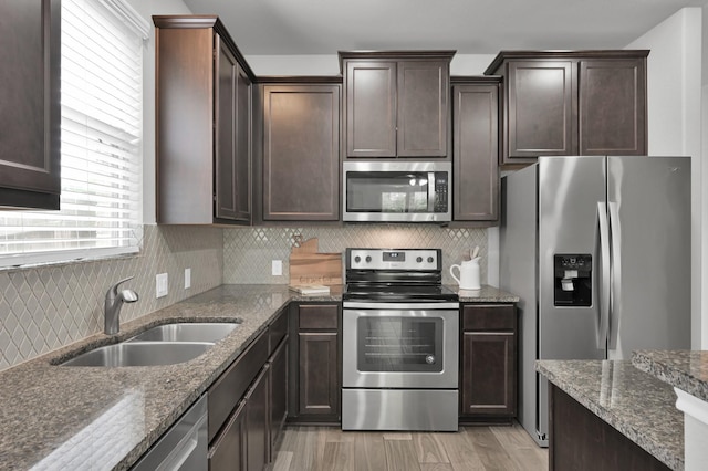 13310 Hidden Valley Dr, Montgomery, TX 77356 - kitchen featuring stainless steel appliances, dark brown cabinetry, dark stone countertops, and light wood-style flooring
