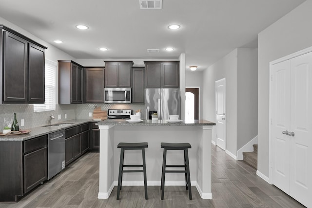 13310 Hidden Valley Dr, Montgomery, TX 77356 - kitchen featuring appliances with stainless steel finishes, backsplash, a breakfast bar, wood finished floors, and recessed lighting