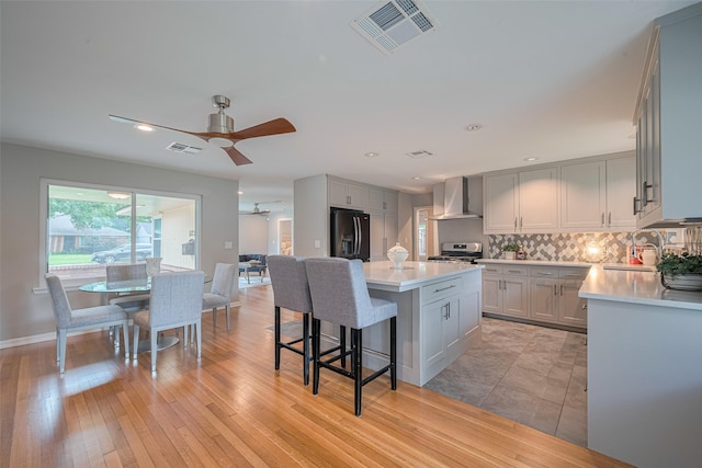 5123 Saxon Dr, Houston, TX 77092 - kitchen with stainless steel stove, wall chimney exhaust hood, light countertops, black fridge with ice dispenser, and recessed lighting