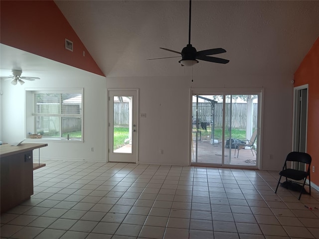 18602 Lippizaner Dr, Cypress, TX 77433 - unfurnished living room with ceiling fan, vaulted ceiling, light tile patterned floors, plenty of natural light, and a textured ceiling