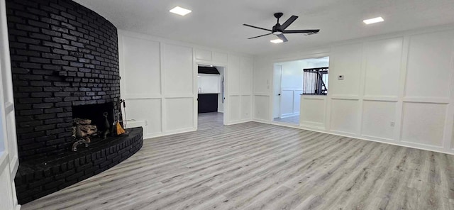47 W Dansby Dr, Galveston, TX 77551 - unfurnished living room featuring a decorative wall, a brick fireplace, light wood-type flooring, and ceiling fan
