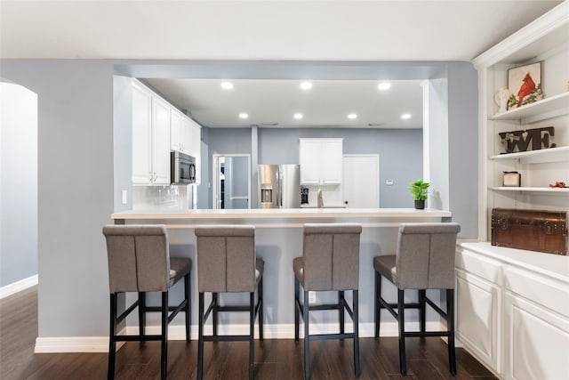 14619 Townsend Ct, Cypress, TX 77429 - kitchen with appliances with stainless steel finishes, a kitchen breakfast bar, recessed lighting, white cabinetry, and dark wood finished floors