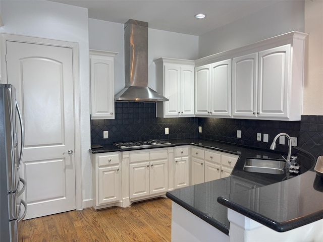 607 Oakley St Unit 5, Houston, TX 77006 - kitchen with wall chimney range hood, stainless steel appliances, dark countertops, white cabinets, and light wood-type flooring
