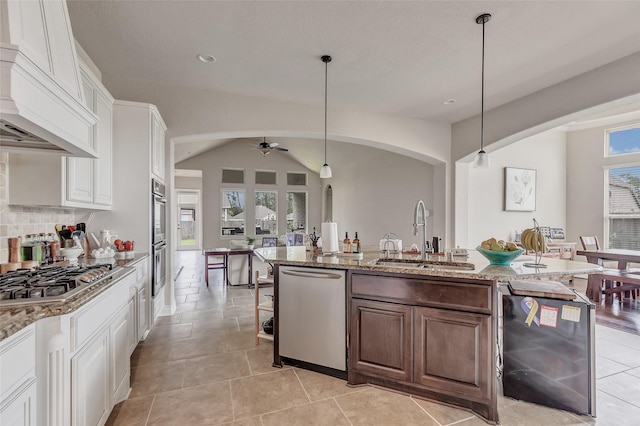 18115 Stari Most Ln, Houston, TX 77044 - kitchen featuring stainless steel appliances, arched walkways, ceiling fan, premium range hood, and light stone counters