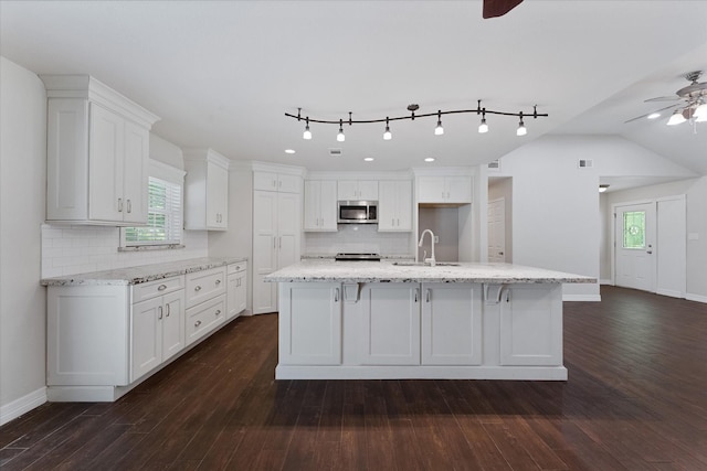 1503 Briar Cliff St, Conroe, TX 77385 - kitchen featuring a ceiling fan, stainless steel microwave, white cabinetry, and decorative backsplash
