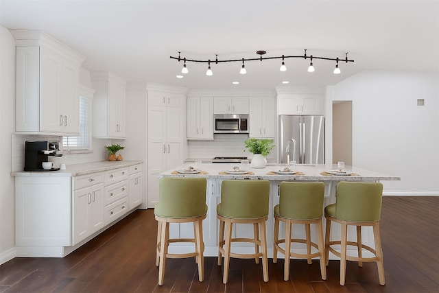 1503 Briar Cliff St, Conroe, TX 77385 - kitchen with stainless steel appliances, white cabinetry, decorative backsplash, dark wood finished floors, and a kitchen island with sink