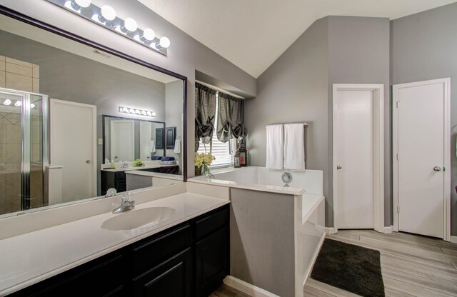 14022 Cypress Falls Dr, Cypress, TX 77429 - bathroom with a shower stall, vanity, vaulted ceiling, a garden tub, and wood finished floors