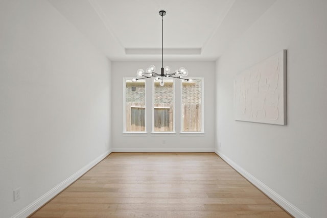 24914 Heather Glade Trl, Tomball, TX 77375 - unfurnished dining area featuring a chandelier, light wood finished floors, and a raised ceiling