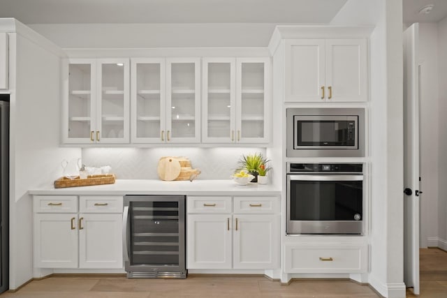 24914 Heather Glade Trl, Tomball, TX 77375 - kitchen with appliances with stainless steel finishes, beverage cooler, white cabinets, backsplash, and light countertops