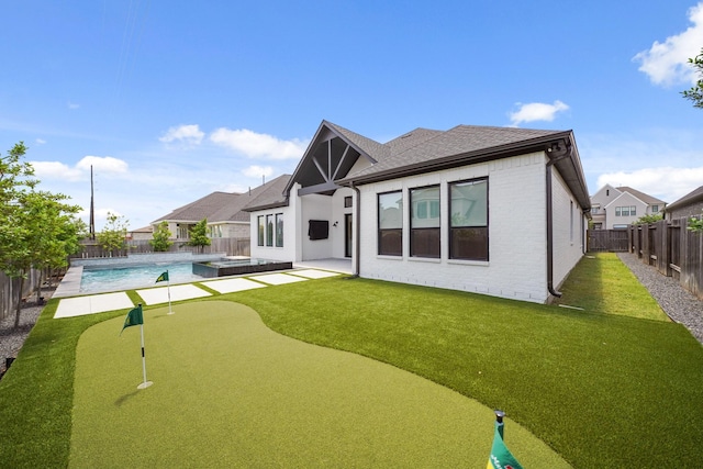 24914 Heather Glade Trl, Tomball, TX 77375 - rear view of house with an area to practice putting, a fenced backyard, brick siding, roof with shingles, and a patio