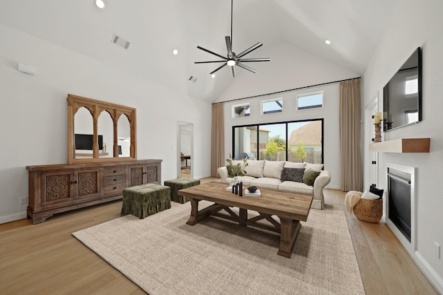 24914 Heather Glade Trl, Tomball, TX 77375 - living area with light wood-type flooring, high vaulted ceiling, a glass covered fireplace, and recessed lighting
