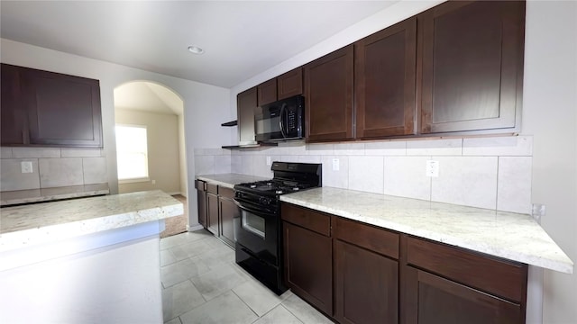 6903 Rosemont Ct, Rosharon, TX 77583 - kitchen featuring black appliances, arched walkways, decorative backsplash, and light stone countertops