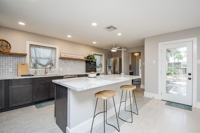 7618 Highmeadow Dr, Houston, TX 77063 - kitchen with open shelves, stainless steel fridge, a kitchen bar, light stone counters, and recessed lighting