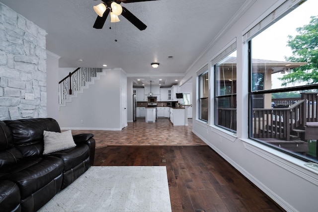 1600 Wimbledon Dr, Huntsville, TX 77340 - living room featuring dark wood-style flooring, ceiling fan, ornamental molding, stairs, and a textured ceiling