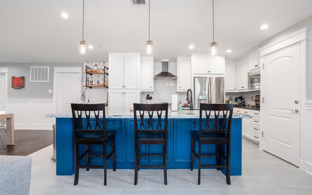 1719 Guese Rd, Houston, TX 77008 - kitchen featuring appliances with stainless steel finishes, wall chimney range hood, backsplash, white cabinets, and recessed lighting