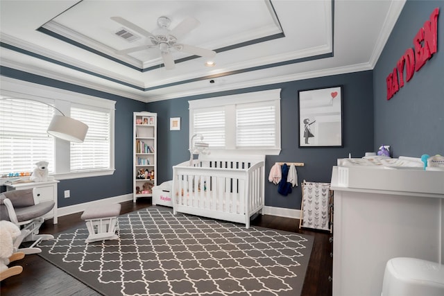 1719 Guese Rd, Houston, TX 77008 - bedroom with a raised ceiling, dark wood-type flooring, ornamental molding, a crib, and ceiling fan