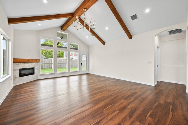 101 Callie St, Smithville, TX 78957 - unfurnished living room featuring a stone fireplace, arched walkways, beamed ceiling, wood finished floors, and a chandelier
