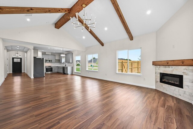 101 Callie St, Smithville, TX 78957 - unfurnished living room featuring a chandelier, a tiled fireplace, dark wood finished floors, beam ceiling, and arched walkways
