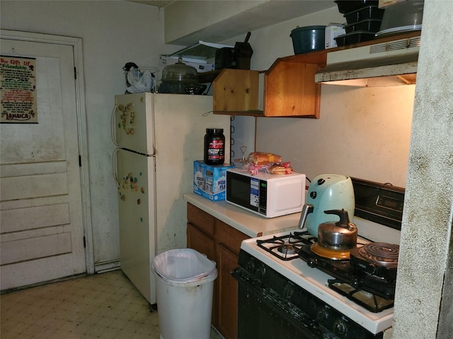 10221 Bretton Dr, Houston, TX 77016 - kitchen featuring gas range oven, white microwave, light countertops, light floors, and brown cabinetry