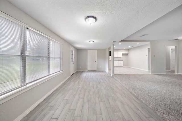 7421 Parker Rd, Houston, TX 77016 - unfurnished living room featuring light wood-style flooring, a textured ceiling, and recessed lighting