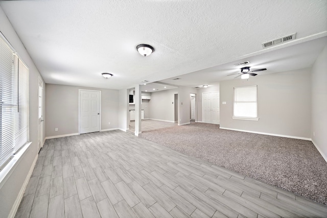 7421 Parker Rd, Houston, TX 77016 - unfurnished living room featuring light wood-type flooring, ceiling fan, and a textured ceiling