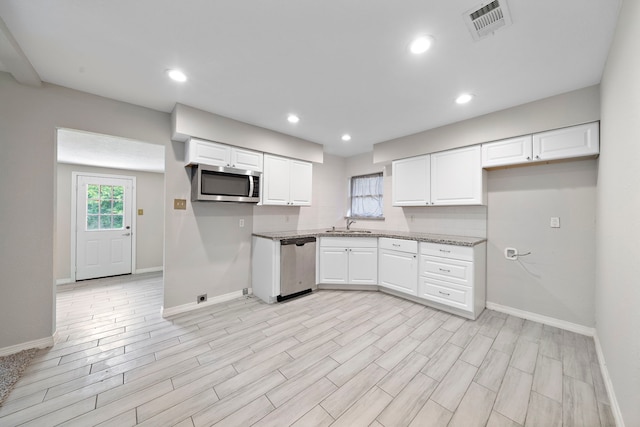 7421 Parker Rd, Houston, TX 77016 - kitchen with appliances with stainless steel finishes, white cabinets, light wood-style flooring, recessed lighting, and light stone counters
