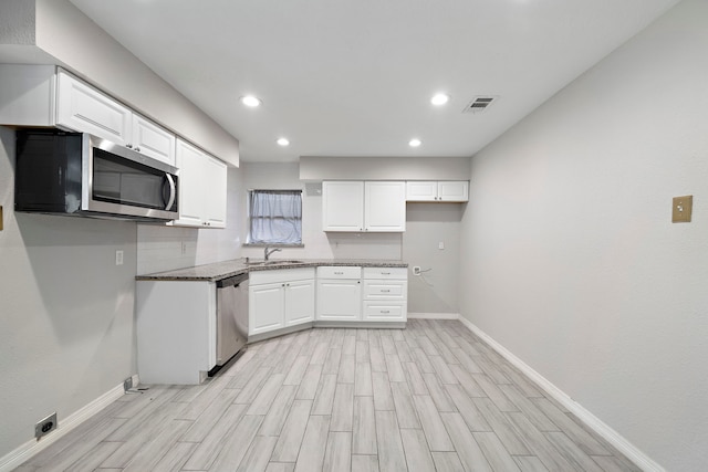 7421 Parker Rd, Houston, TX 77016 - kitchen with appliances with stainless steel finishes, light wood-type flooring, white cabinetry, recessed lighting, and light stone counters