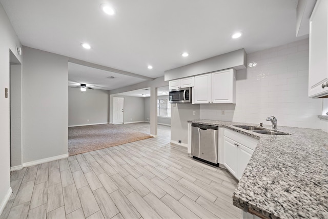 7421 Parker Rd, Houston, TX 77016 - kitchen with appliances with stainless steel finishes, white cabinetry, light wood finished floors, light stone counters, and recessed lighting
